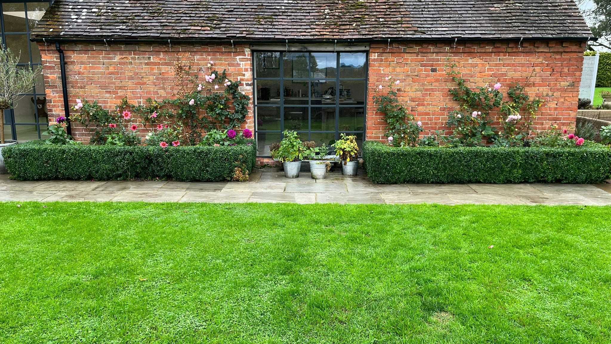 A bright green striped lawn in front of a brick garden building.