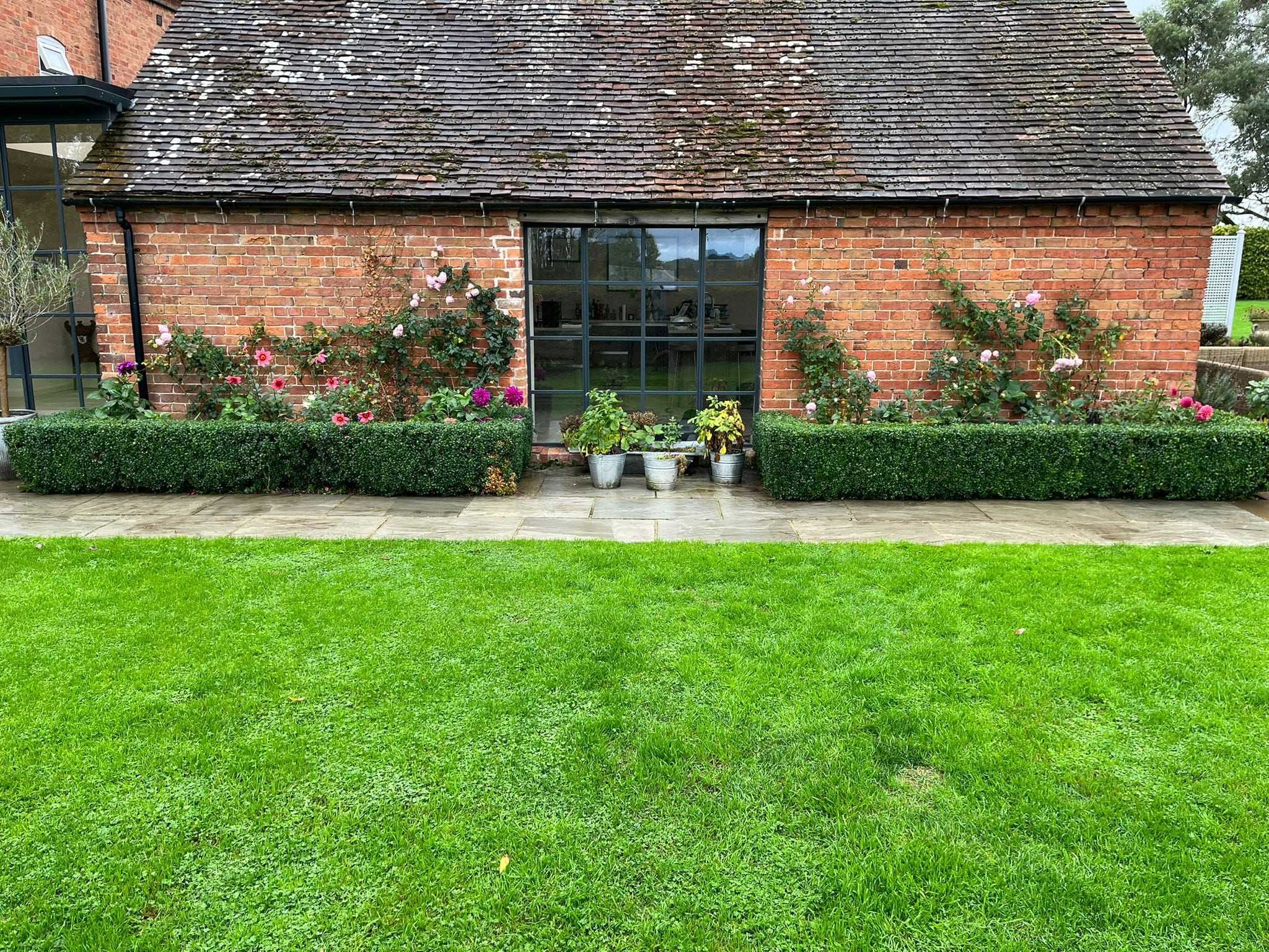 A bright green striped lawn in front of a brick garden building.