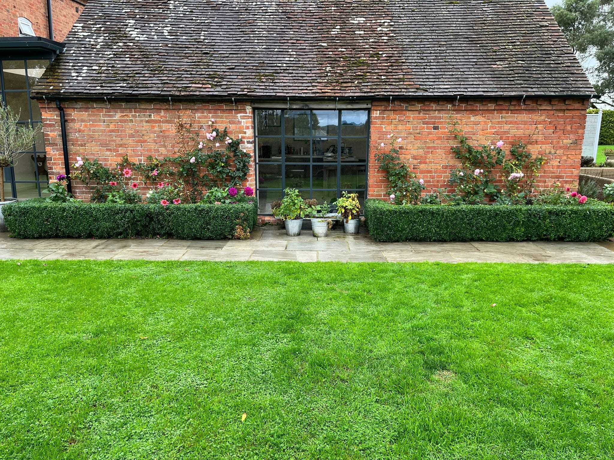 A bright green striped lawn in front of a brick garden building.